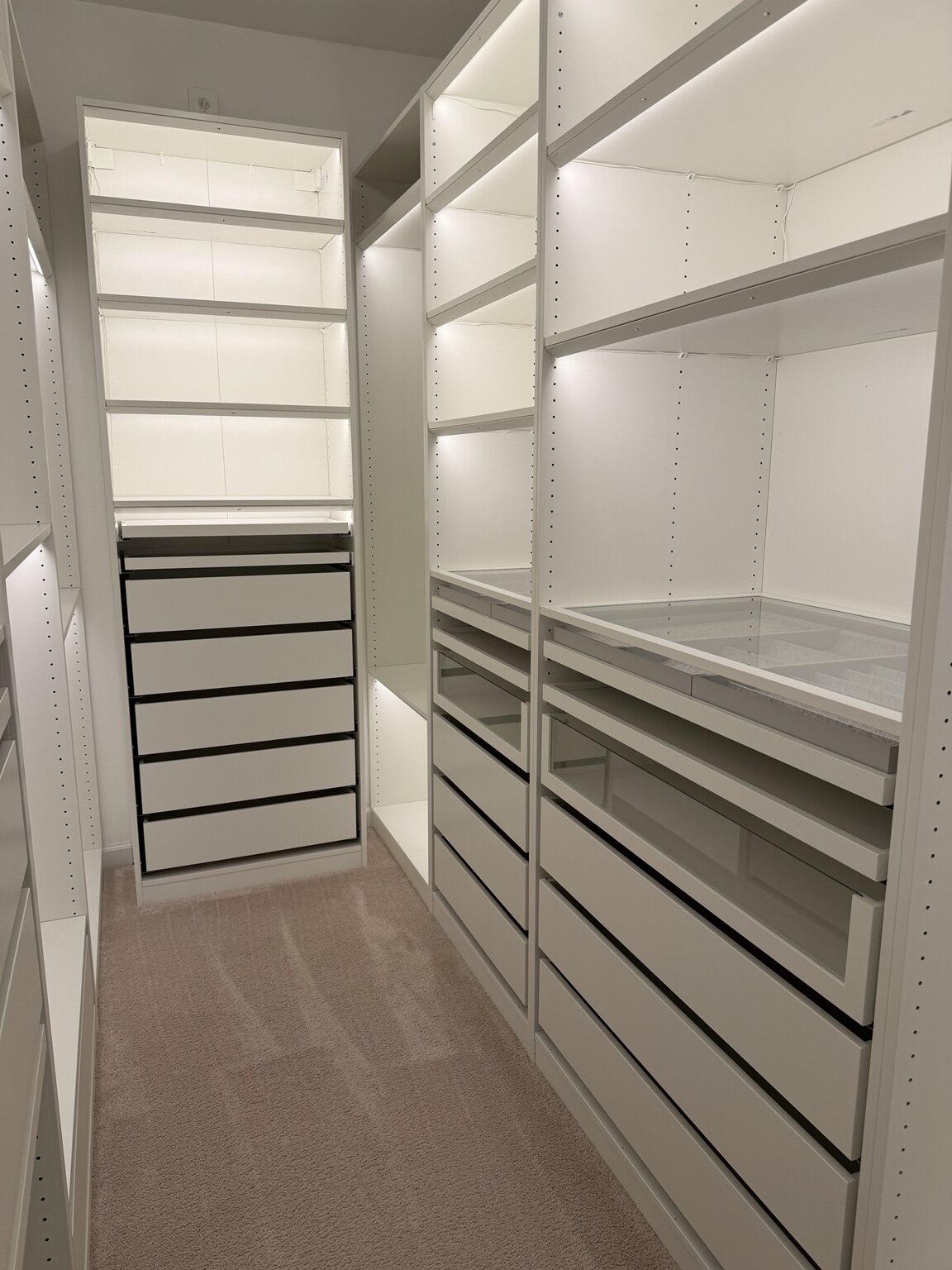 Illuminated walk-in closet with drawers and shelving