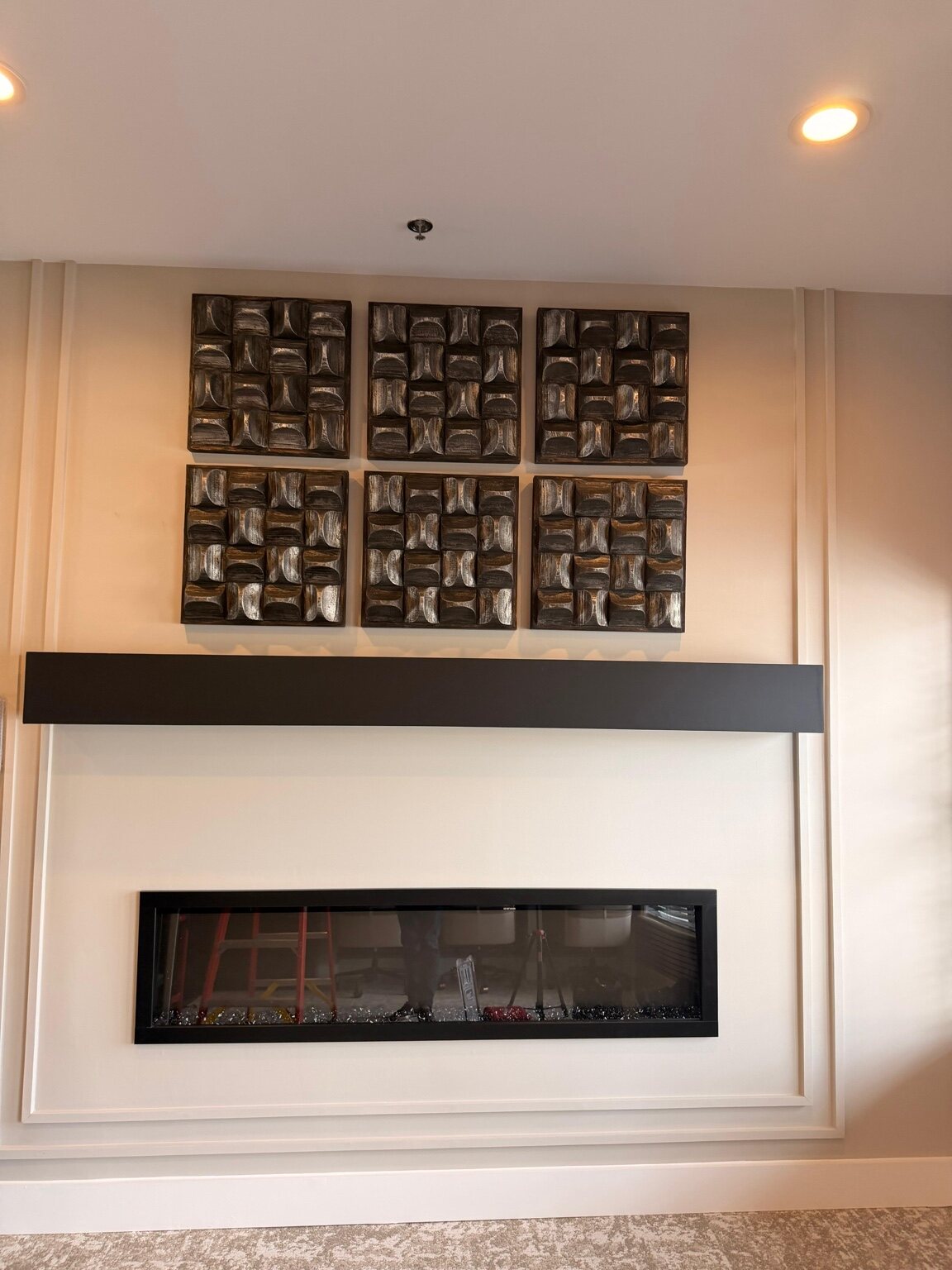 Artwork installed above a modern linear fireplace
